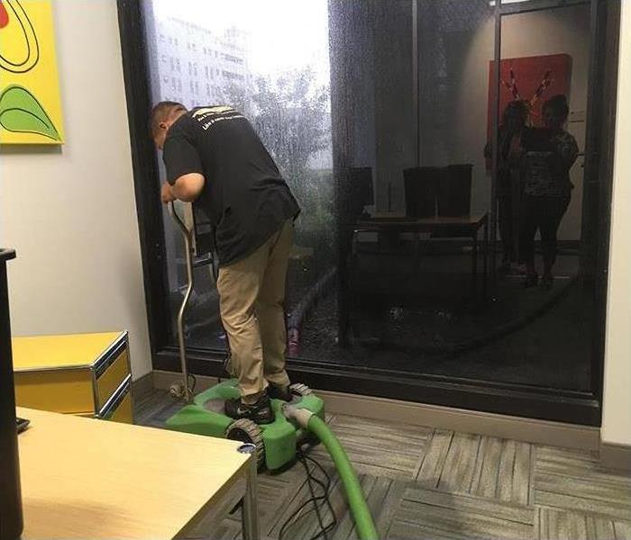 SERVPRO employee cleaning water from the floor after water damage
