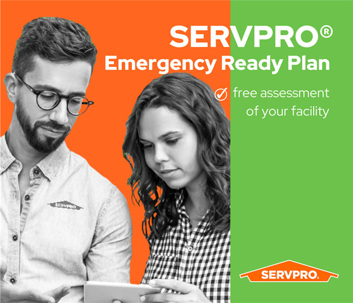 two black and white people holding an ipad with the SERVPRO ERP app, orange background, green stripe on right, SERVPRO logo